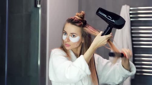 Woman Styling Hair in Bathroom with Hair Dryer