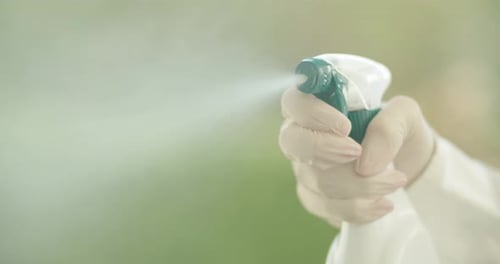 Hand Sprays Cleaning Product toward Camera