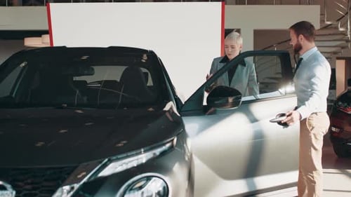 Cheerful Blond Woman Sitting in Modern Car with Open Door and Looking Aside