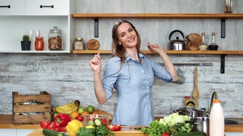 Woman Dancing in Kitchen with Fresh Vegetables