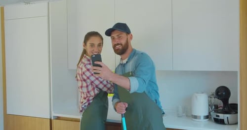 Man and Woman As a Professional Cleaners in Uniform Standing Together with Phone During the Break in