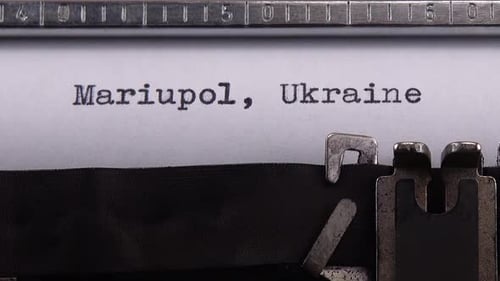 Typing name of Ukrainian city "Mariupol, Ukraine" on retro typewriter.