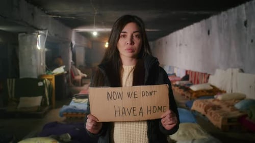 Portrait of a Sad Armenian Woman in a Large Bomb Shelter Holding a Sign
