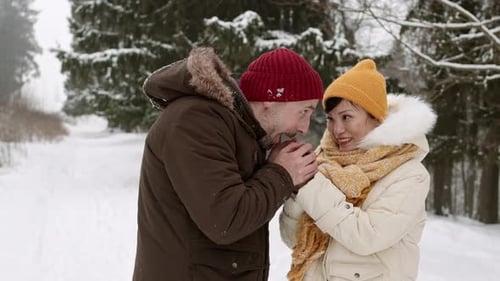 Loving Couple Warms Hands in Snowy Winter Forest