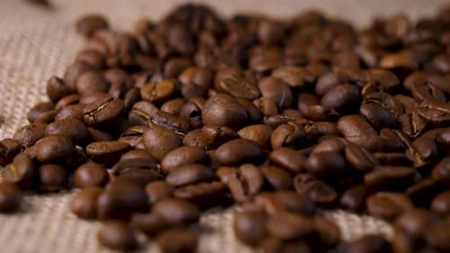 Pile of Roasted Coffee Beans on Burlap Background