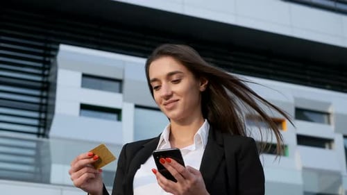Woman Using Phone and Holding Credit Card