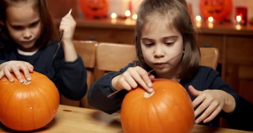 Two Girls Carving Pumpkins for Halloween