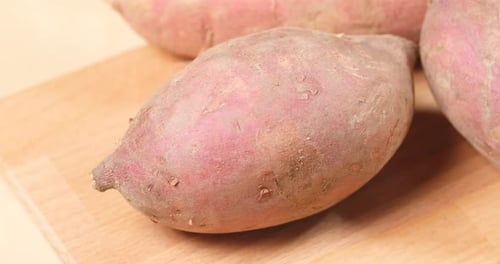 Close up of Several Sweet Potatoes on Cutting Board
