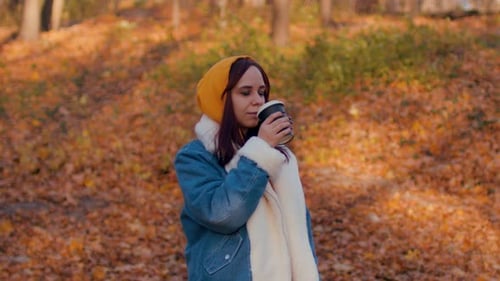Young Woman Drinking Coffee in Autumn Forest