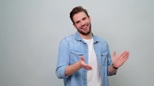 Portrait d'un jeune homme joyeux applaudissant ou applaudissant sur fond gris clair