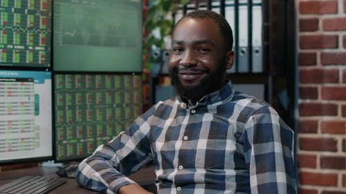 Retrato de hombre afroamericano con monitores múltiples para trabajar