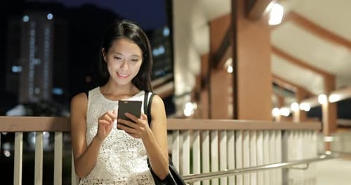 Woman using smart phone in city at night
