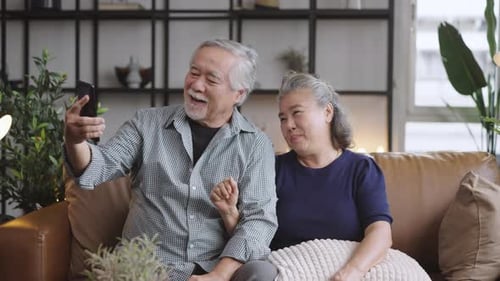 Senior Couple Using Smartphone on Couch at Home