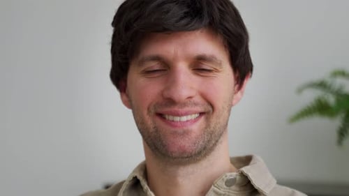 An Attractive Confident Man Looking Into the Camera Sitting in a Modern Living Room