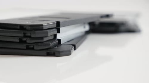 Black floppy disc classic magnetic storage media on white 4K 2160p 30fps UHD tilting footage - Lot o