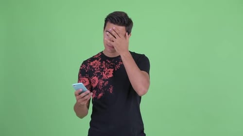 Young Adult Looks at Phone with Thoughtful Expression