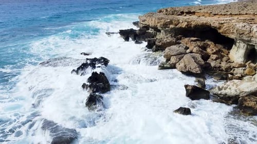 Sea Washes the Rocky Shore Above Aerial Shot Flying Over Coastline Cliffside with Blue Pure Water