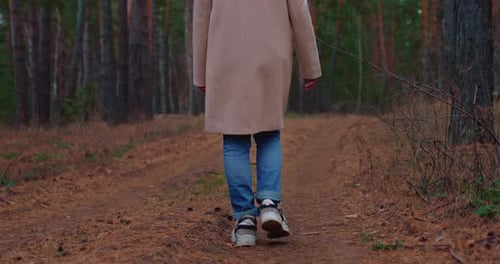 Girl in Jeans Walks Through the Autumn Coniferous Forest