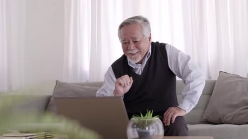 Senior Man Video Calling on Laptop at Home