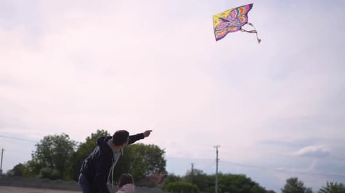 Father and Daughter Fly Kite on Cloudy Day