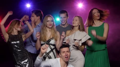 Happy Young Adults Dancing Together with Stage Lighting