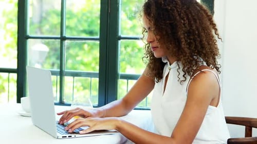 Woman Using Laptop and Drinking Juice Indoors