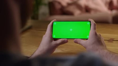 Handheld Camera Young Man at Home Holding Chroma Key Green Screen Smartphone Watching Content
