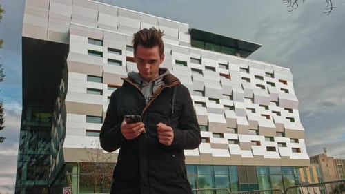 Teenager on the Street with a Phone in His Hands Reads a Message on the