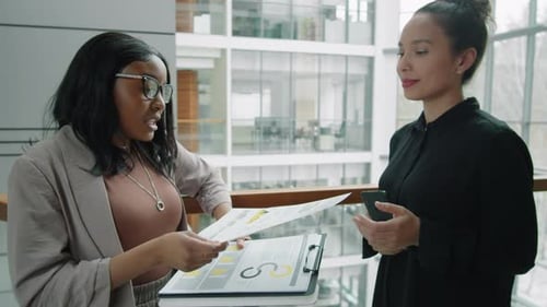 Diverse Female Colleagues Discussing Documents in Business Center