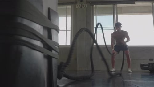 strong man working out with battle rope, fitness exercise challenge in sport gym