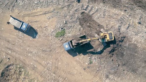 Aerial of Backhoe Loading Garbage Truck at Landfill