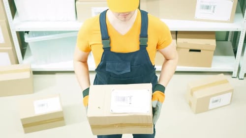 Vernachlässigter Lagerarbeiter oder Kurier hält ein beschädigtes Paket