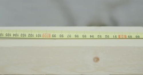 Man Uses Ruler Tape to Mark Wooden Plank Size
