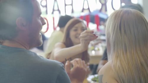 Woman sharing salad with friend in restaurant