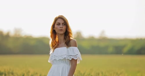 Beautiful Young Woman Walks on a Summer Day in the Field