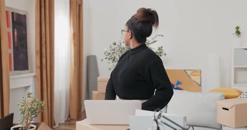 Woman Typing on Laptop at Home Among Boxes