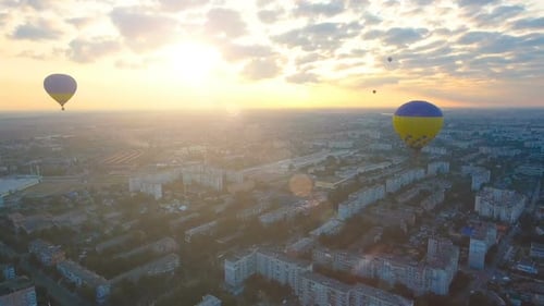 Couple of Hot Air Balloons Floating Over City Against Rising Sun, Early Flights