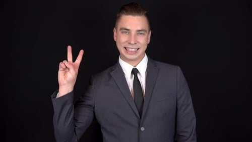 Smiling Man Gestures Peace Sign in Suit