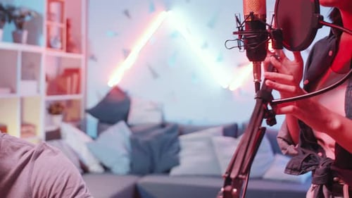 Asian Woman Recording Song with Help of Black Male Friend in Home Studio