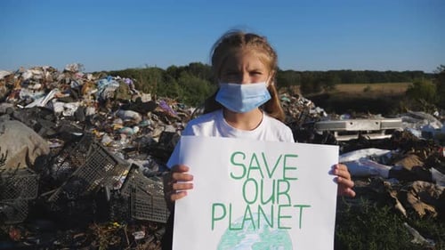 Child Holding Save Our Planet Sign at Landfill