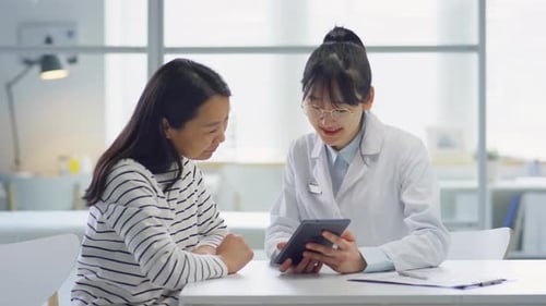 Doctor Consults with Patient Using Tablet in Bright Office