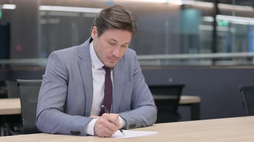 Businessman Writing at Office Desk, Corporate Environment