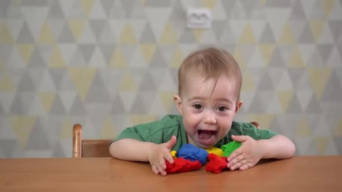 Baby Playing with Colorful Clay at Table Indoors