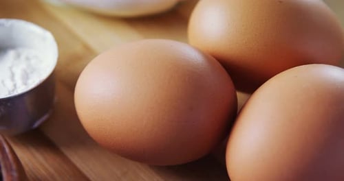 Various ingredients and brown eggs on wooden table 4k
