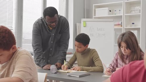 Dedicated Teacher Helping Students in Bright Classroom