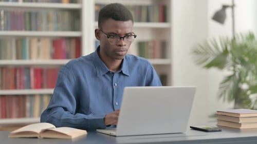 Young African Man Working on Laptop in Office