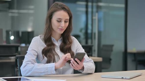 Woman Using Smartphone Device at Desk in Office