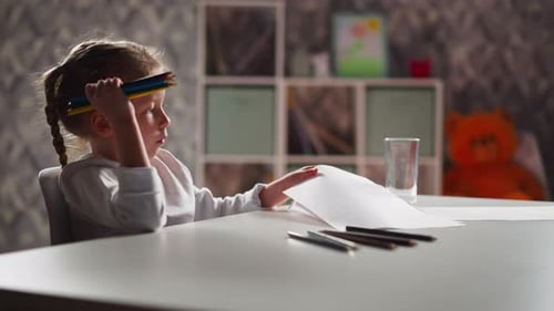 Little Artist Turns Paper and Draws Picture with Pencils