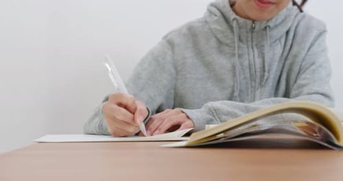 Person Writing With Pen At Wood Table