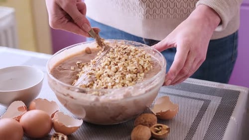 Making Walnut Chocolate Cake Adding Walnuts to Raw Dough in a Glass Bowl